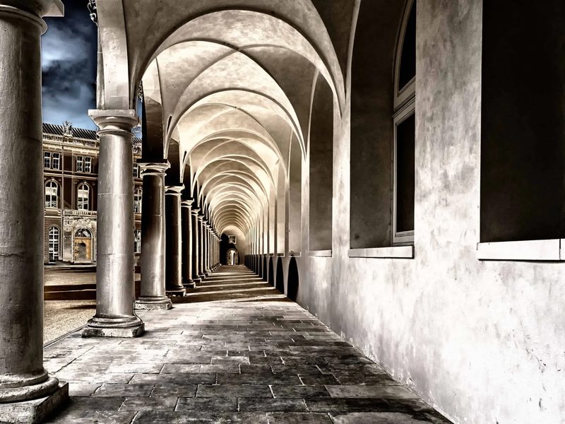 Galería abovedada de un pórtico monumental, con la columnata alineada en fuga hacia el fondo